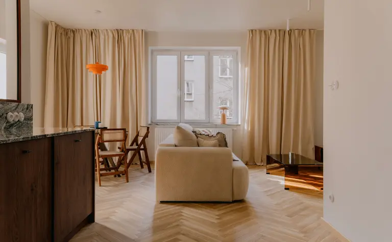 Wnętrze salonu w stylu quiet luxury, soft minimalizm i vintage z beżową sofą i drewnianymi akcentami.