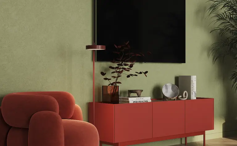 Wnętrze salonu z czerwonym fotelem, zieloną ścianą i drewnianą podłogą. Styl art deco, glamour, industrialny.