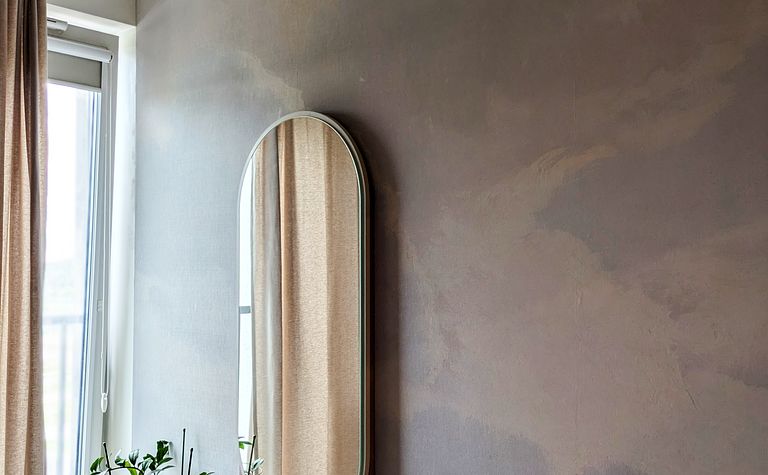 Sypialnia w stylu soft minimalizm z lustrem i rośliną.