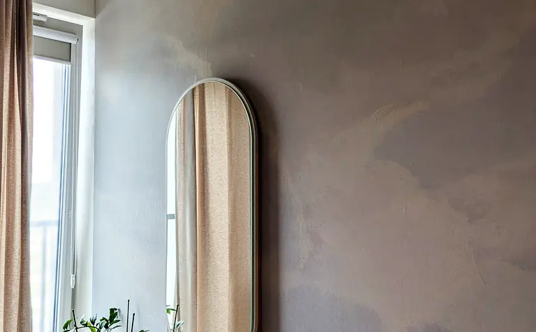 Sypialnia w stylu soft minimalizm z lustrem i rośliną.