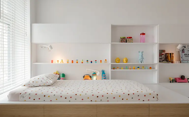 Pokój dziecięcy w stylu eklektycznym i minimalistycznym z białym łóżkiem i kolorowymi zabawkami.