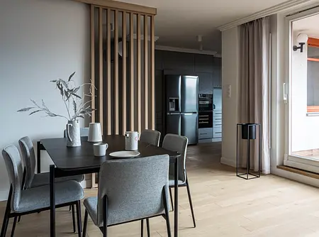 Wnętrze jadalni z szarymi krzesłami, drewnianym stołem, minimalistycznym designem.