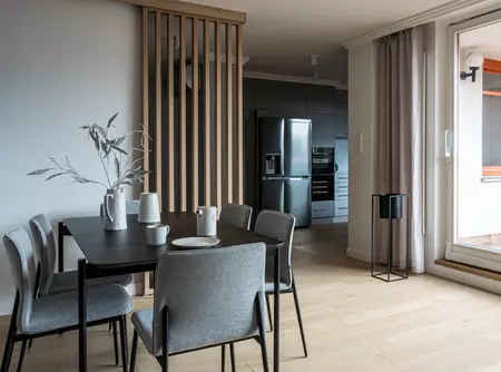 Wnętrze jadalni z szarymi krzesłami, drewnianym stołem, minimalistycznym designem.