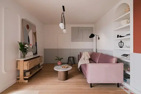 Wnętrze salonu w stylu art deco, eklektycznym i vintage z różową sofą i drewnianym stolikiem.