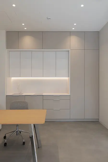 Biuro w stylu japandi i minimalistycznym z szarymi meblami i drewnianym biurkiem.