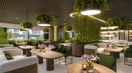 Wnętrze restauracji z roślinami, drewnianymi meblami i jasnymi dekoracjami.