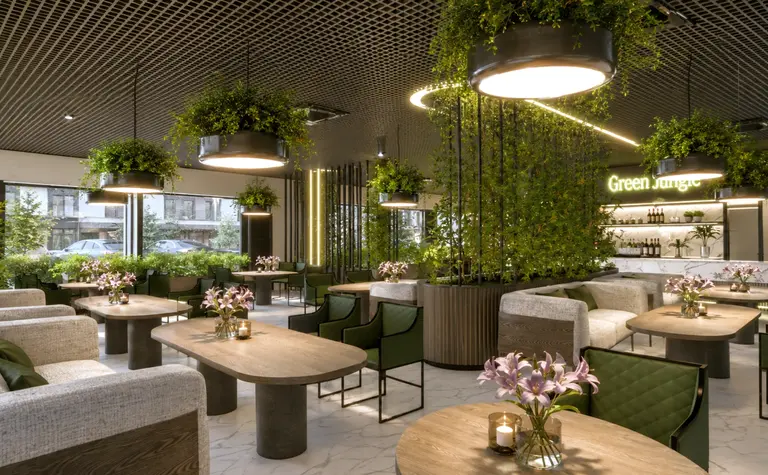 Wnętrze restauracji z roślinami, drewnianymi meblami i jasnymi dekoracjami.