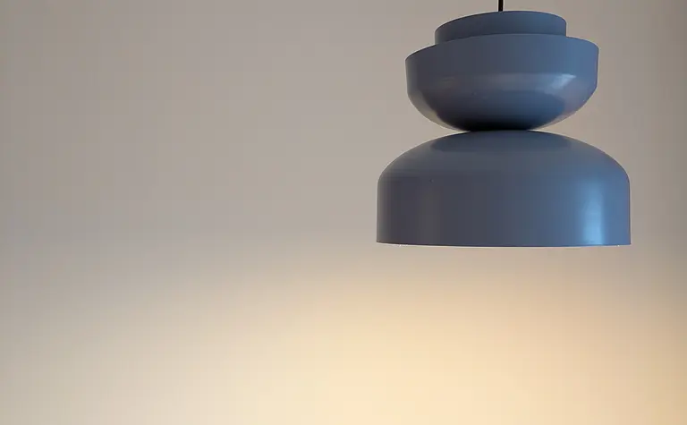 Wnętrze sypialni w stylu soft minimalizm z nowoczesną lampą.