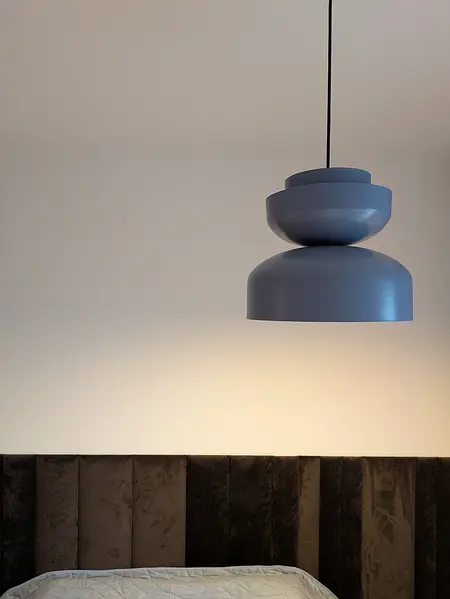 Wnętrze sypialni w stylu soft minimalizm z nowoczesną lampą.