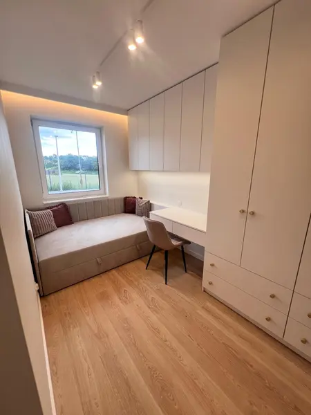 Wnętrze pokoju z białymi meblami, biurkiem i kanapą w stylu glamour i nowoczesnym.