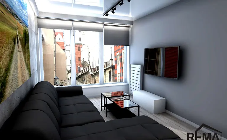 Wnętrze salonu z czarną sofą, szklanym stolikiem i nowoczesnym TV w stylu industrialnym.