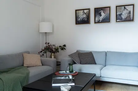 Wnętrze salonu z szarymi sofami, złotym lampionem i dekoracjami roślinnymi, styl minimaluxe, nowoczesny.