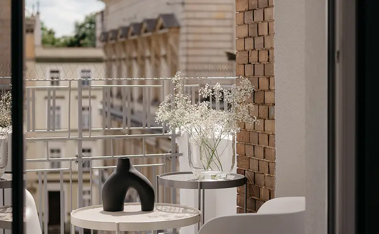 Balkon w stylu eklektycznym z minimalistycznymi meblami i kwiatami.