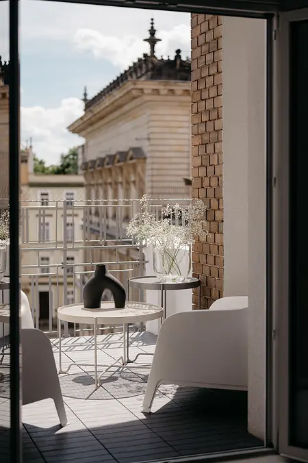 Balkon w stylu eklektycznym z minimalistycznymi meblami i kwiatami.