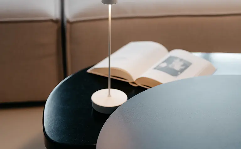 Nowoczesne wnętrze salonu z minimalistycznym stolikiem i lampą w stylu quiet luxury.