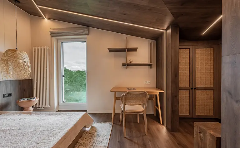 Wnętrze poddasza w stylu boho i skandynawskim z drewnianymi meblami i jasnymi akcentami.