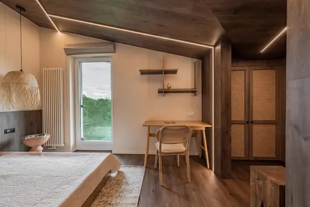 Wnętrze poddasza w stylu boho i skandynawskim z drewnianymi meblami i jasnymi akcentami.