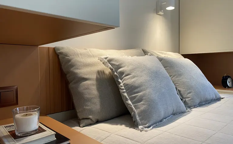 Sypialnia w stylach japandi, minimalistycznym, skandynawskim i współczesnym z beżowymi poduszkami.