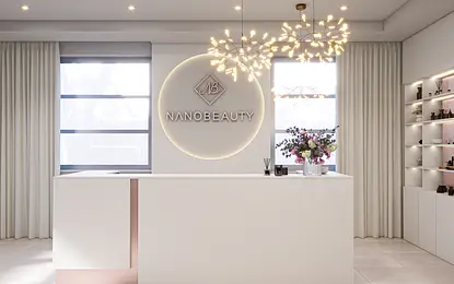 Recepcja w minimalistycznym wnętrzu z białym blatem, kwiatami i nowoczesnym oświetleniem.