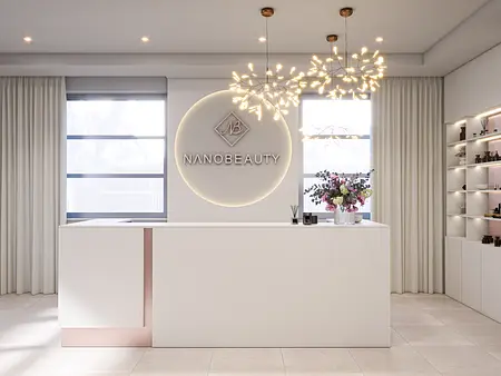 Recepcja w minimalistycznym wnętrzu z białym blatem, kwiatami i nowoczesnym oświetleniem.