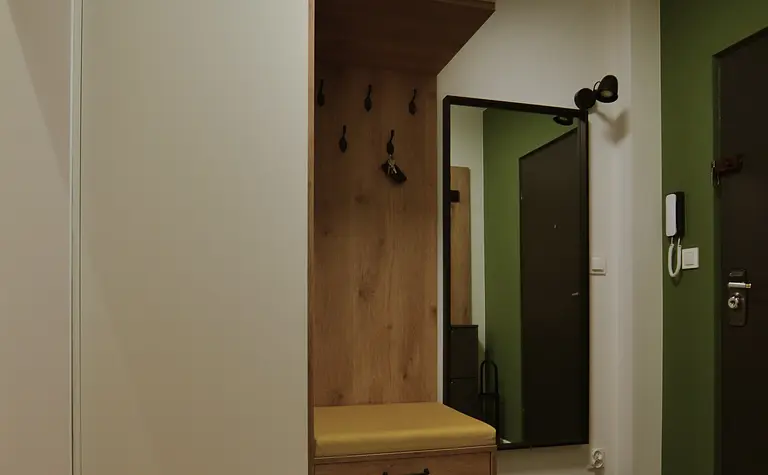 Przedpokój z minimalistycznym i skandynawskim designem, białe meble, drewniane elementy.