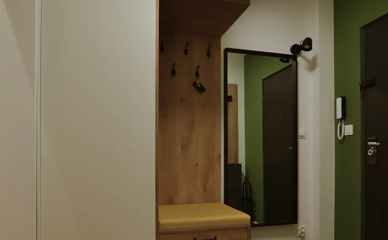 Przedpokój z minimalistycznym i skandynawskim designem, białe meble, drewniane elementy.