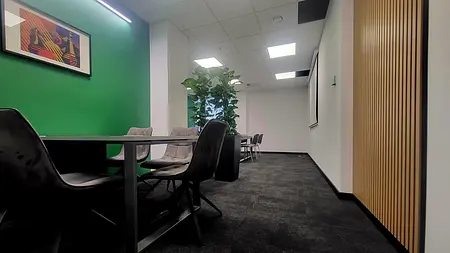 Wnętrze biura z zieloną ścianą, nowoczesnym meblem i roślinnością.