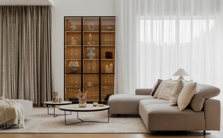 Nowoczesny salon w stylu japandi i minimalistycznym z jasną kanapą i drewnianymi dodatkami.