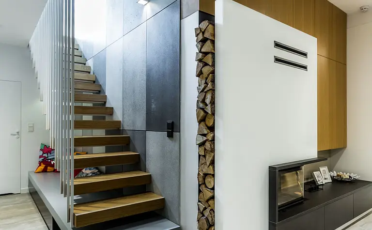 Wnętrze z drewnianymi schodami, kominkiem i minimalistycznymi detalami. Styl industrialny i skandynawski.