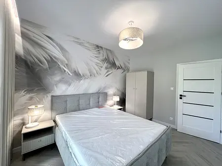 Wnętrze sypialni w stylu boho i współczesnym z szarym łóżkiem.
