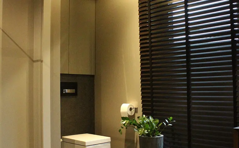 Toaleta z minimalistycznym wystrojem, szarymi kafelkami i nowoczesnymi detalami.