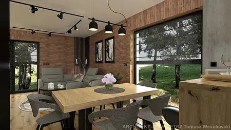 Wnętrze salonu w stylu industrialnym z drewnianym stołem, szarymi fotelami i ceglaną ścianą.