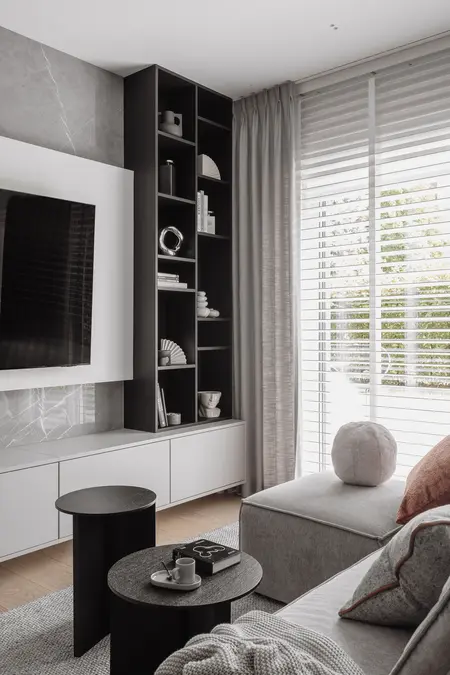Wnętrze salonu z szarym narożnikiem i czarnymi stolikami, nowoczesny design.