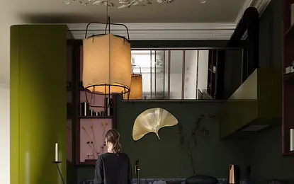 Eklektyczna kuchnia z zielonymi meblami, okrągłym drewnianym stołem i dekoracjami.