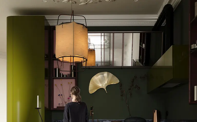 Eklektyczna kuchnia z zielonymi meblami, okrągłym drewnianym stołem i dekoracjami.