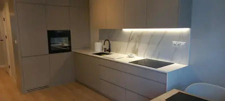 Wnętrze nowoczesnej kuchni z jasnymi meblami i marmurowym blatem, minimalistyczne akcenty.