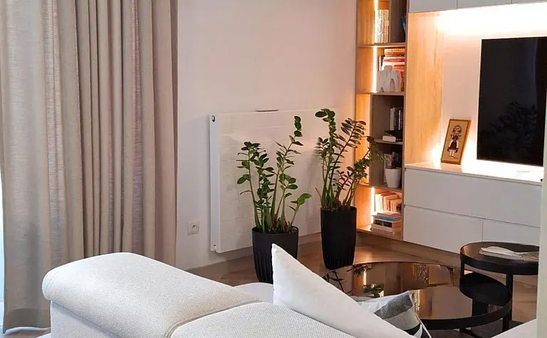 Wnętrze salonu z nowoczesnym wystrojem, biała sofa, rośliny.