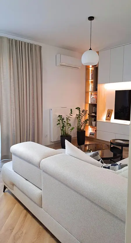 Wnętrze salonu z nowoczesnym wystrojem, biała sofa, rośliny.