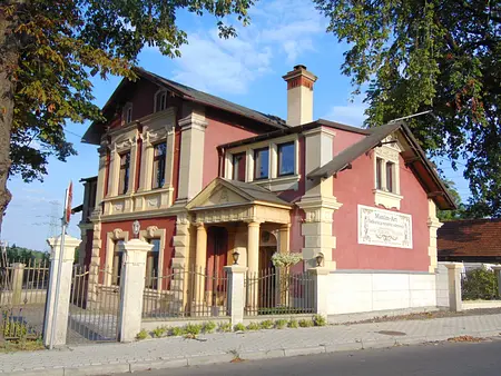 Ekstremalnie stylowa fasada domu z czerwonym tynkiem i białymi detalami architektonicznymi.