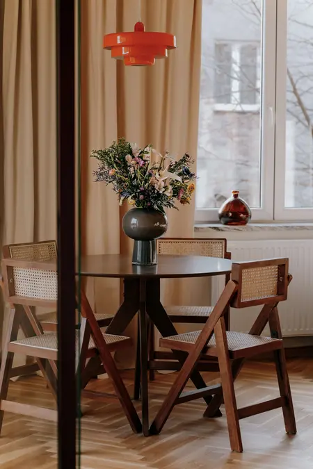 Wnętrze jadalni z drewnianym stołem, krzesłami i bukietem kwiatów, styl quiet luxury.