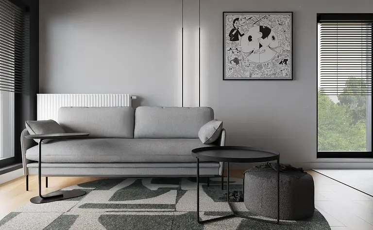 Wnętrze minimalistycznego salonu z szaro-białą sofą, czarnym stolikiem i dekoracyjnymi obrazami.