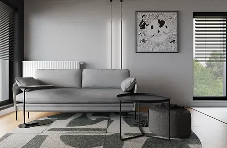 Wnętrze minimalistycznego salonu z szaro-białą sofą, czarnym stolikiem i dekoracyjnymi obrazami.