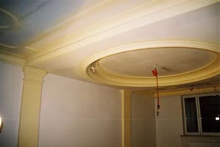 Wnętrze pokoju z żółtym sufitem i oknem, jasne ściany.