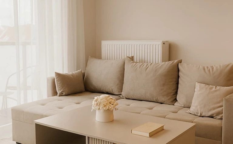 Wnętrze salonu z beżową sofą, stolikiem i oknem, styl glamour i minimalistyczny.