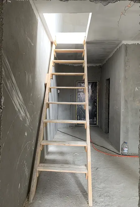 Korytarz z drewnianymi schodami i szarymi ścianami w stylu eklektycznym.