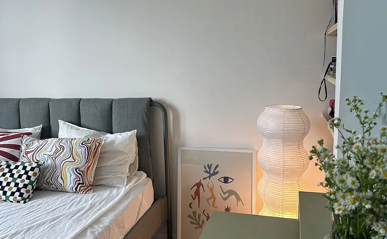 Sypialnia w stylu boho, eklektycznym i skandynawskim z szarym łóżkiem i kolorowymi akcentami.