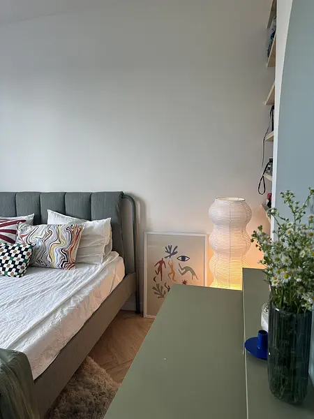 Sypialnia w stylu boho, eklektycznym i skandynawskim z szarym łóżkiem i kolorowymi akcentami.