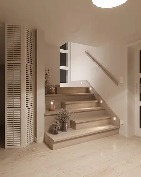 Minimalistyczna klatka schodowa z drewnianymi schodami i dekoracjami.