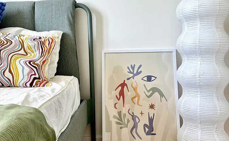 Sypialnia z łóżkiem, lampą i kolorowymi poduszkami w stylach boho, eklektycznym i skandynawskim.