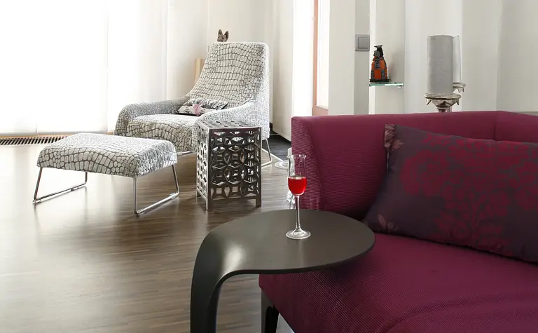 Wnętrze salonu z fioletową kanapą, drewnianą podłogą i dekoracjami eklektycznymi.